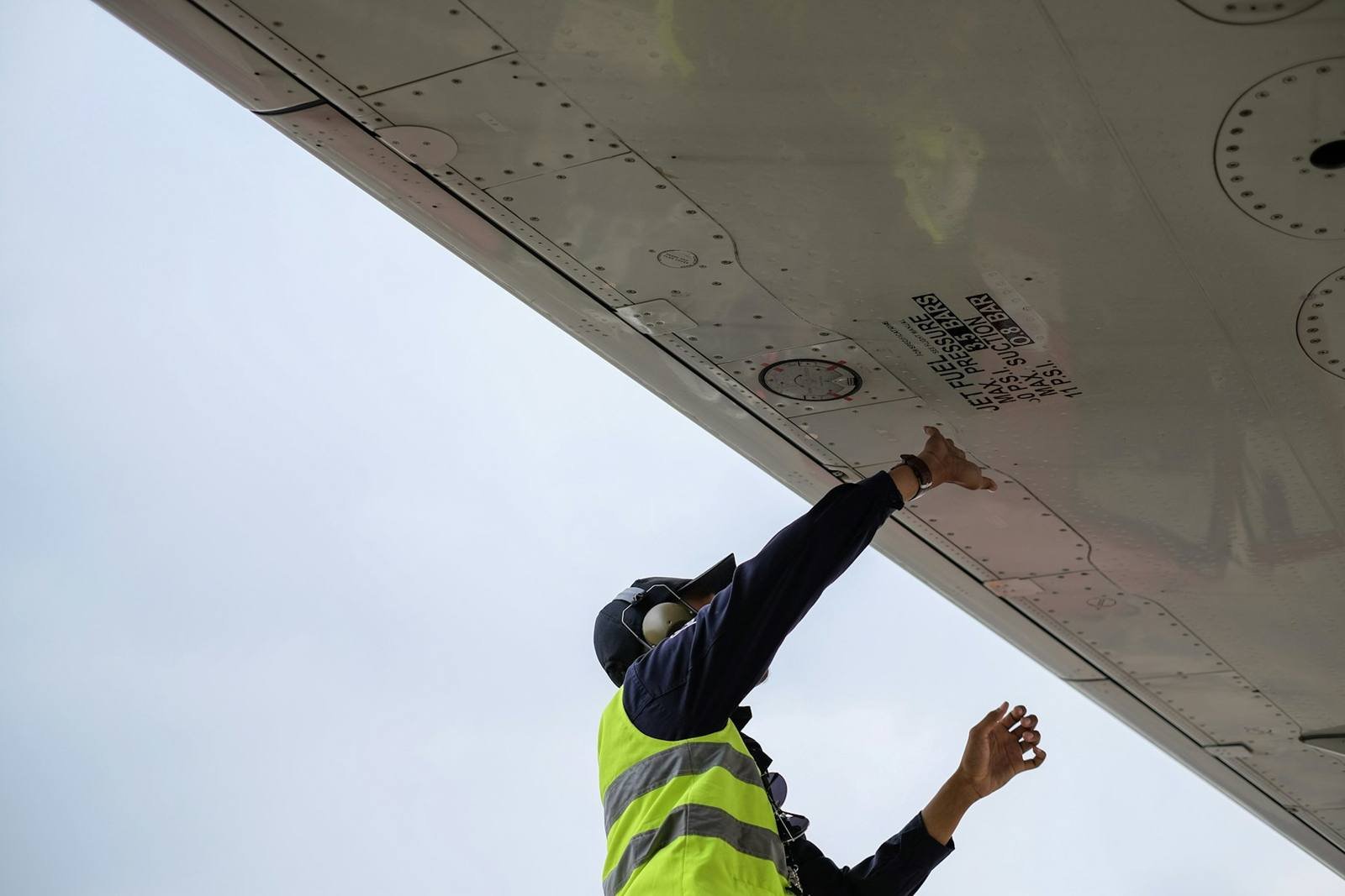 Ground engineer inspecting the underside of an aircraft wing